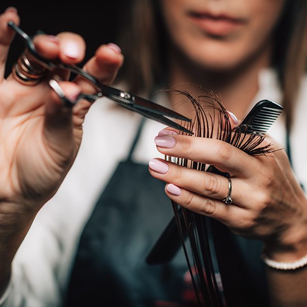 Close-up of a hairdresser cutting woman’s hair.