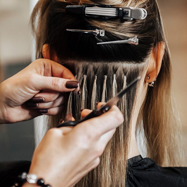 Professional hair extensions being added to a woman's hair.